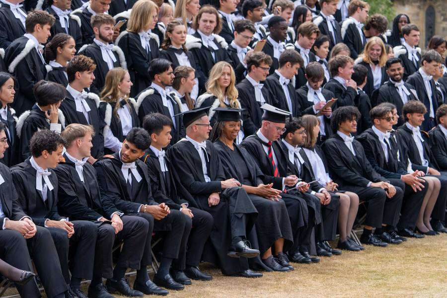 Graduates sitting in rows in academic gowns for a group photograph